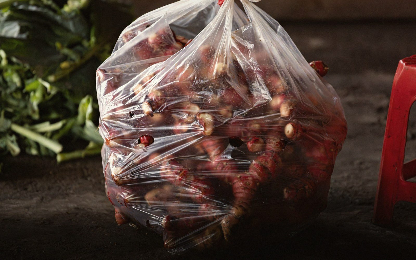 Fresh root tubers tied in a clear plastic bag on a market floor