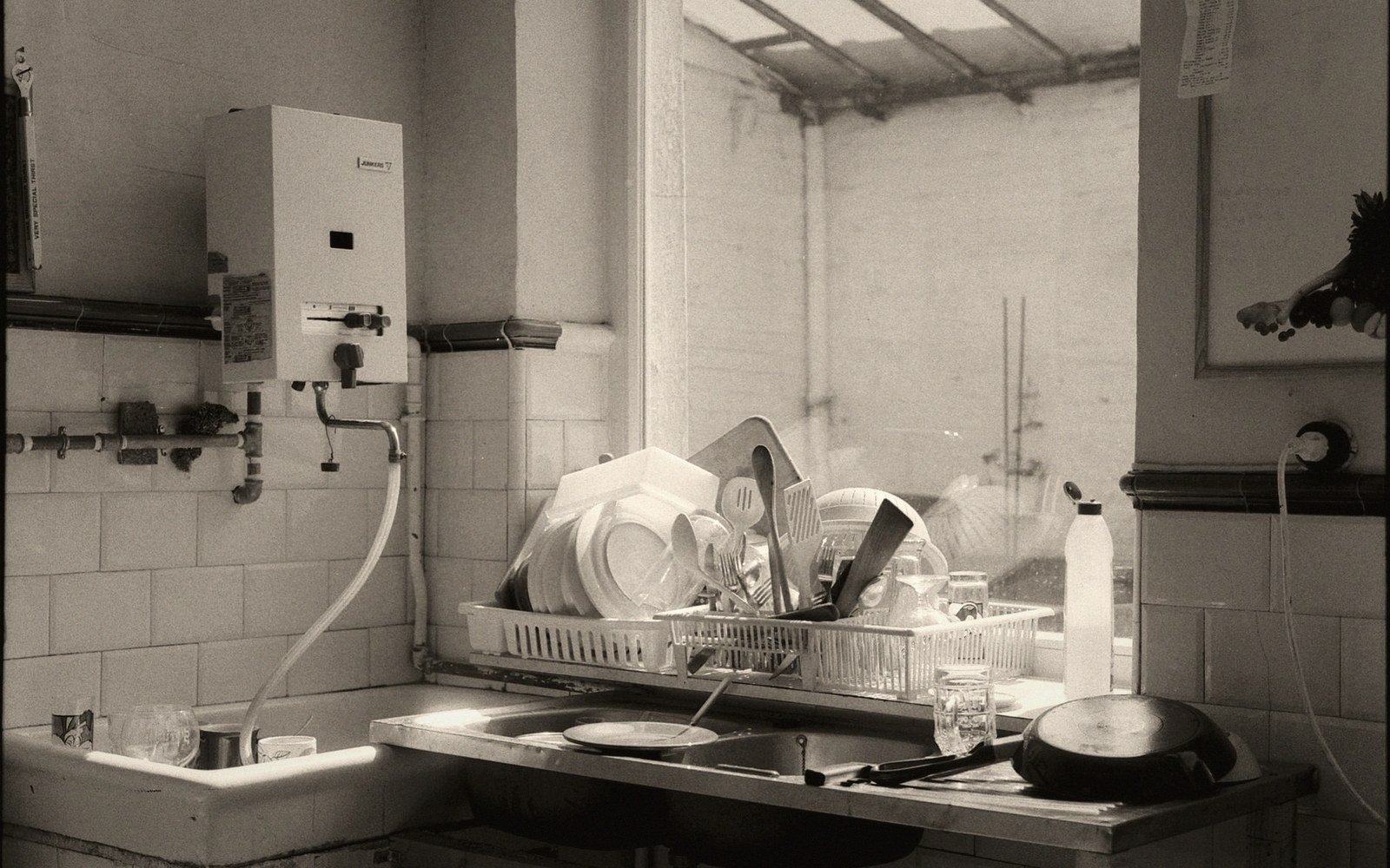 Dishes drying in a rack beside a kitchen sink with a wall-mounted water heater