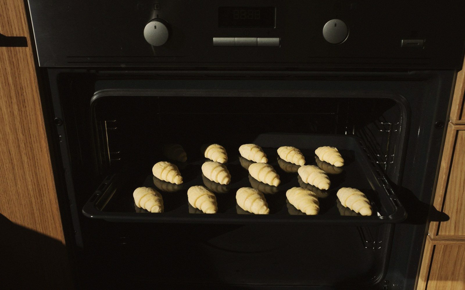 Unbaked croissants arranged on a tray in an open built-in oven