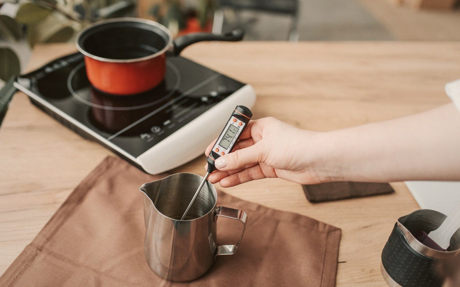 A probe thermometer in a pan of warm soy milk